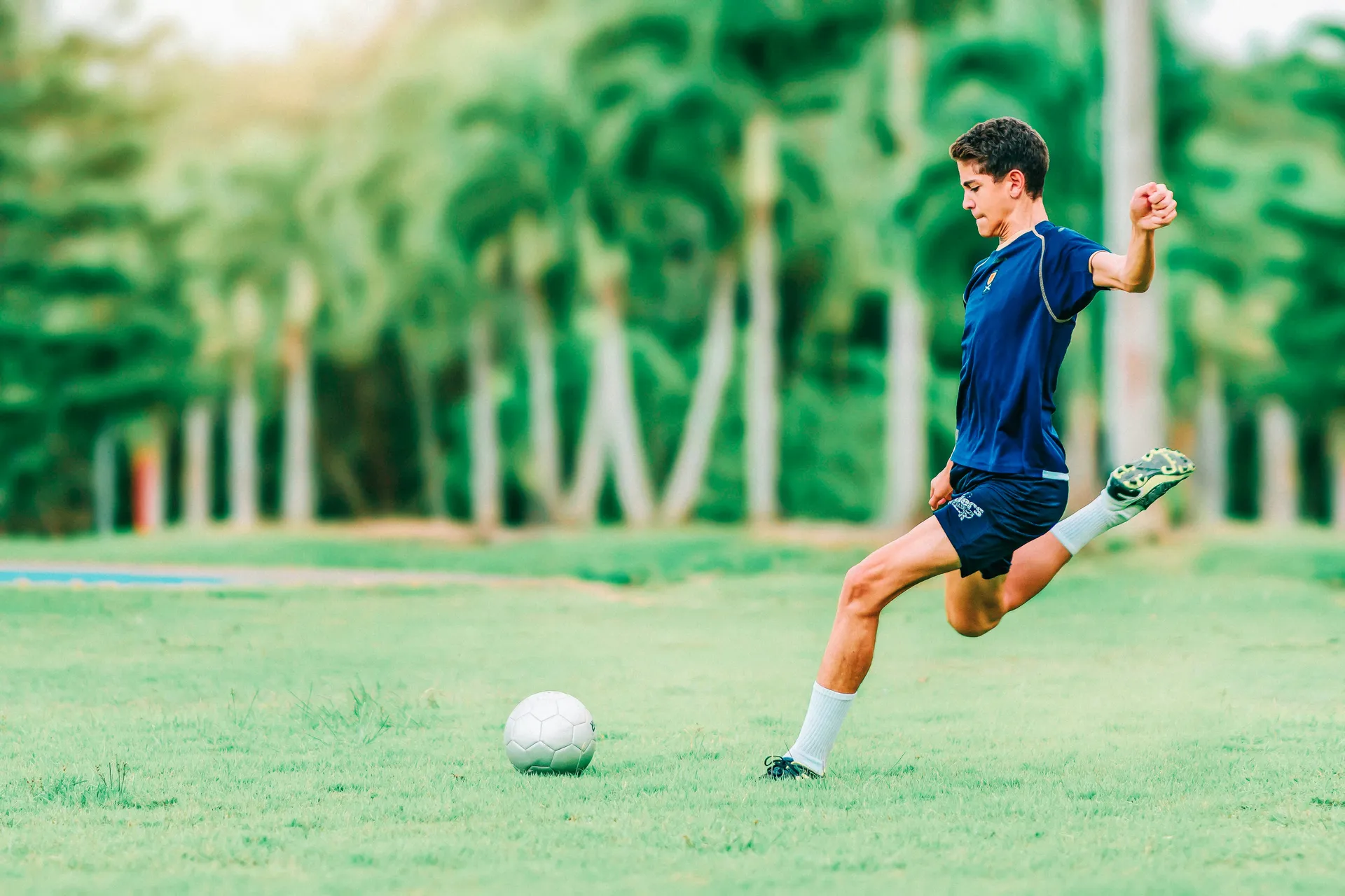 A young footballer striking the ball on a grass pitch, small-sided play like a five-a-side league